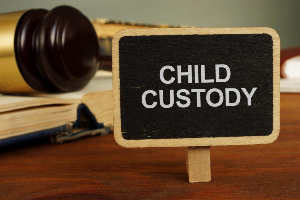 A legal gavel and old law books next to a small chalkboard with "Child Custody" written on it, representing child custody law in Utah.