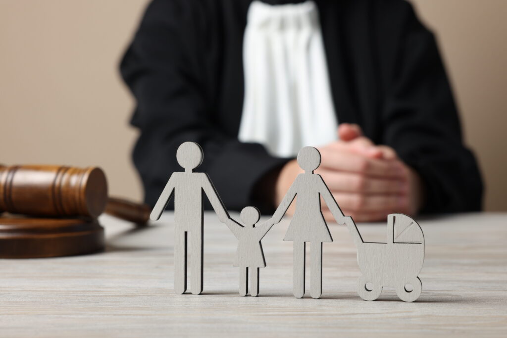 Wooden family figures and gavel on a judge's desk, symbolizing custody cases.
